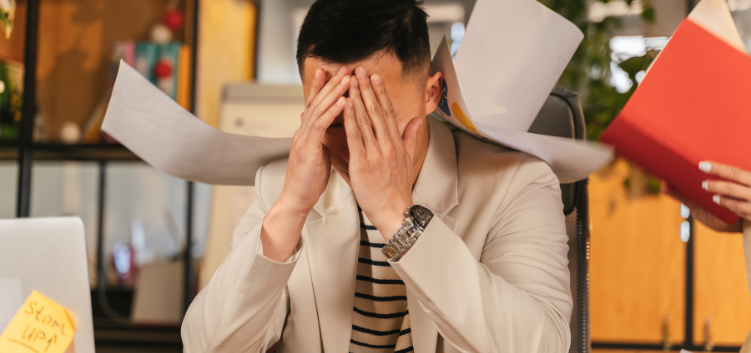 distressed man at desk with paper flying around him